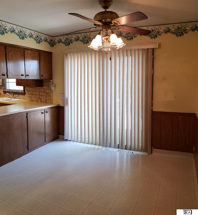 14930 Holmes St, Omaha, NE 68137 - kitchen featuring a ceiling fan, light countertops, plenty of natural light, wainscoting, and a sink