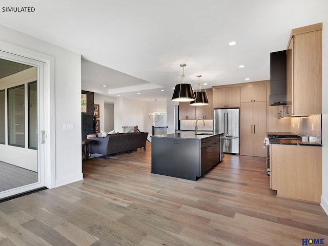 kitchen featuring high quality appliances, a sink, open floor plan, tasteful backsplash, and light wood finished floors