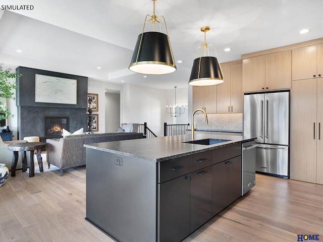 kitchen featuring stainless steel appliances, a sink, light wood-type flooring, dark countertops, and recessed lighting
