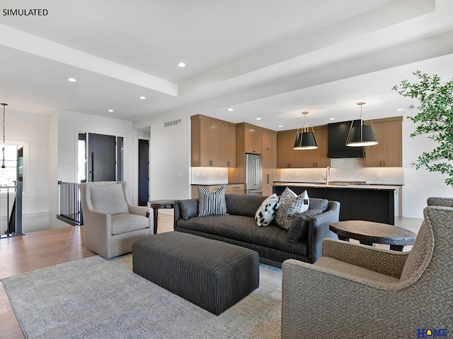 living area featuring recessed lighting, light wood-type flooring, and a raised ceiling
