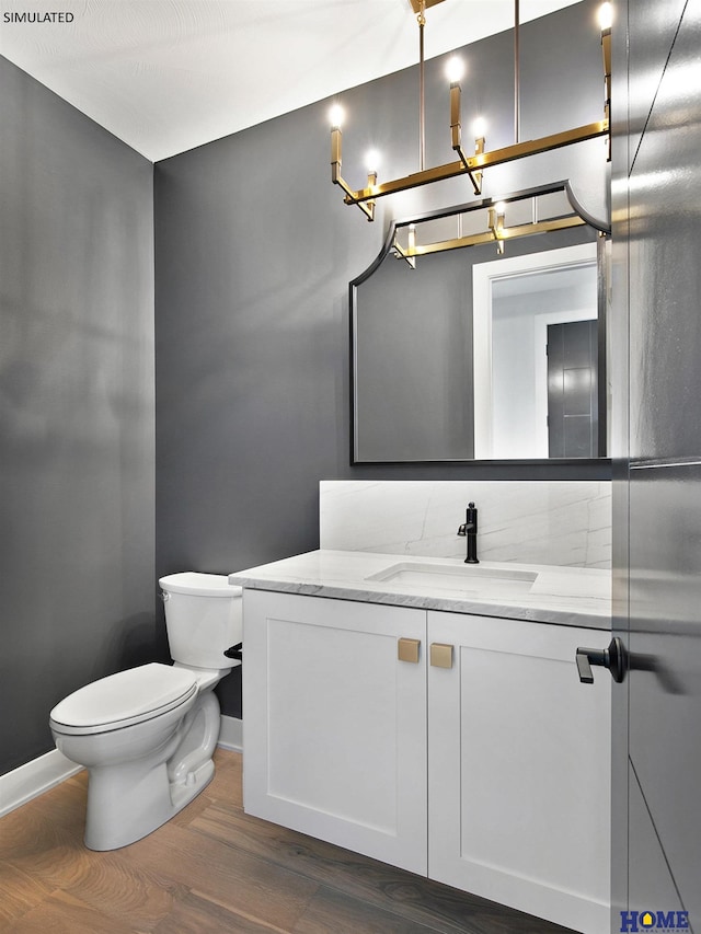bathroom featuring a chandelier, toilet, baseboards, vanity, and wood finished floors