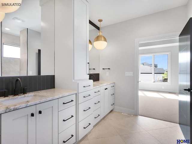 bathroom featuring healthy amount of natural light, two vanities, and tile patterned flooring