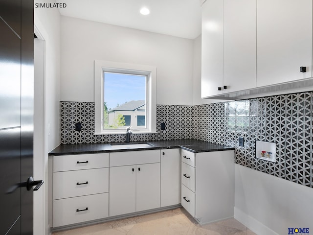 kitchen featuring a sink, white cabinets, tasteful backsplash, dark countertops, and recessed lighting