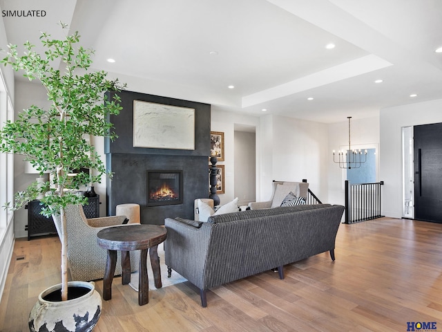 living room featuring light wood-style floors, a chandelier, a glass covered fireplace, and recessed lighting