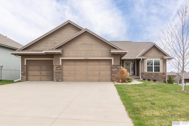 craftsman house with stone siding, a front yard, a garage, and driveway