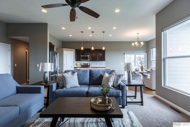 living room with light colored carpet, a ceiling fan, baseboards, a chandelier, and recessed lighting