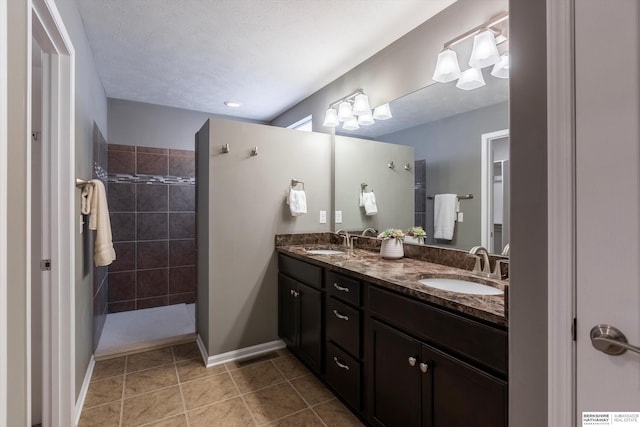 full bathroom featuring walk in shower, double vanity, tile patterned floors, and baseboards