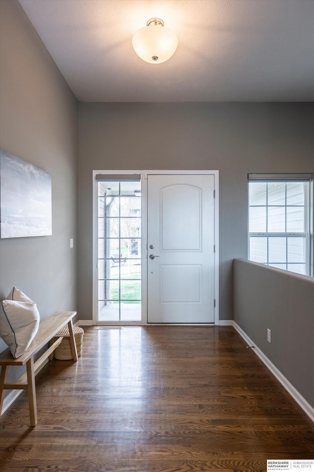 doorway featuring dark wood-style floors and baseboards