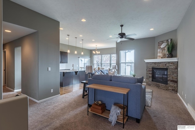 living room featuring carpet, ceiling fan, recessed lighting, baseboards, and a stone fireplace