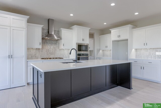 21108 Arlington St, Elkhorn, NE 68022 - kitchen with wall chimney range hood, a sink, stainless steel appliances, backsplash, and a center island with sink