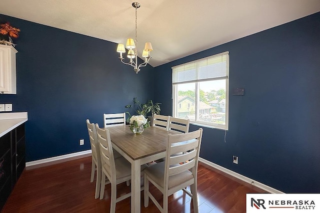 dining area with dark wood-style flooring, a chandelier, and baseboards