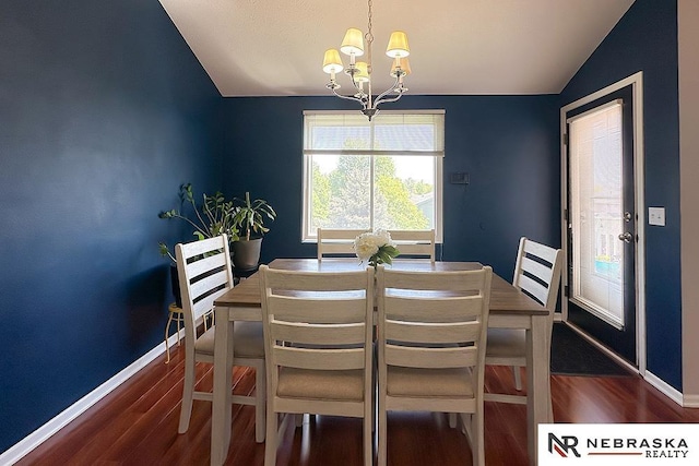 dining room featuring lofted ceiling, a chandelier, wood finished floors, and baseboards