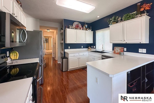kitchen featuring stainless steel electric range oven, a sink, dark wood-style flooring, white cabinets, and a peninsula