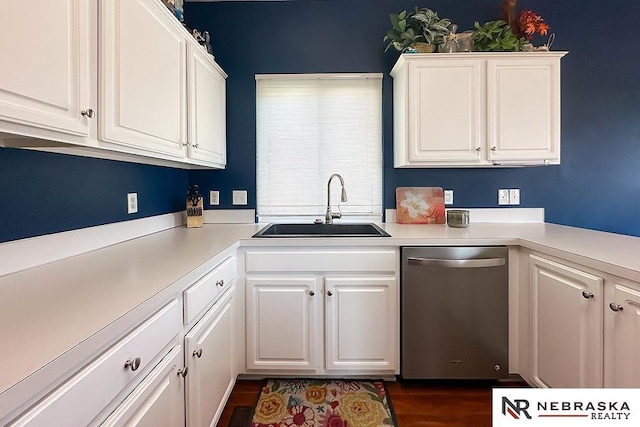 kitchen featuring stainless steel dishwasher, a sink, white cabinetry, and light countertops