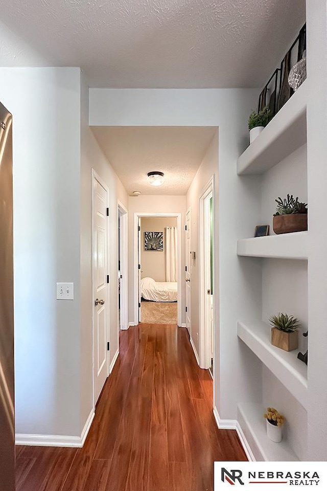 hall with dark wood-style flooring and baseboards