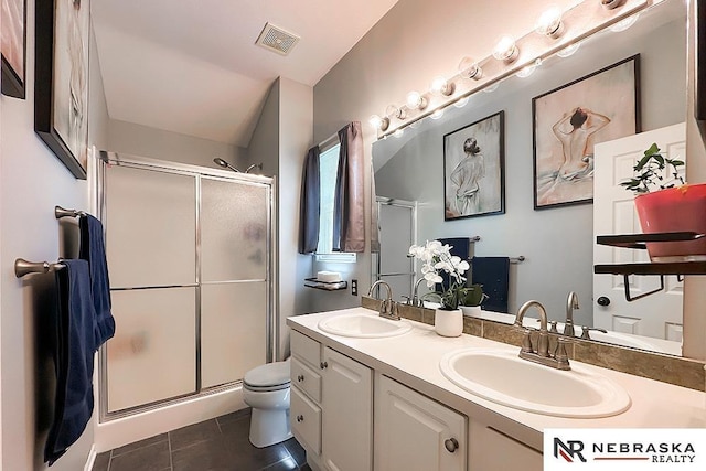 bathroom with a shower stall, double vanity, toilet, and tile patterned floors