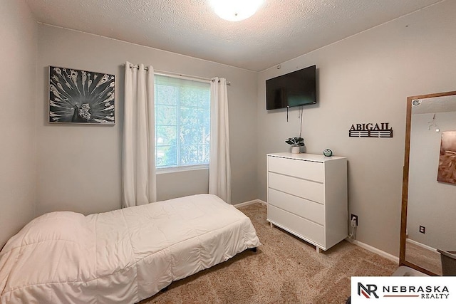 bedroom featuring light carpet, a textured ceiling, and baseboards