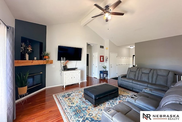 living area with ceiling fan, wood finished floors, beam ceiling, a large fireplace, and baseboards