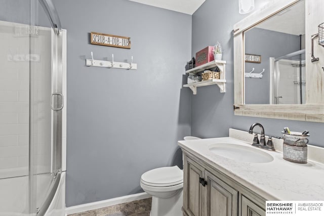 bathroom featuring toilet, vanity, baseboards, and enclosed tub / shower combo