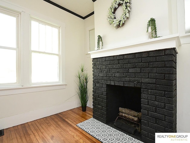 detailed view of wood finished floors, a fireplace, and ornamental molding