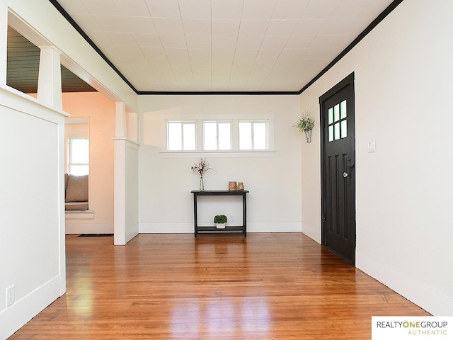 entryway featuring light wood-type flooring, crown molding, and baseboards