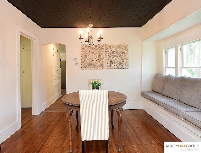 dining space featuring a chandelier, baseboards, arched walkways, and hardwood / wood-style flooring