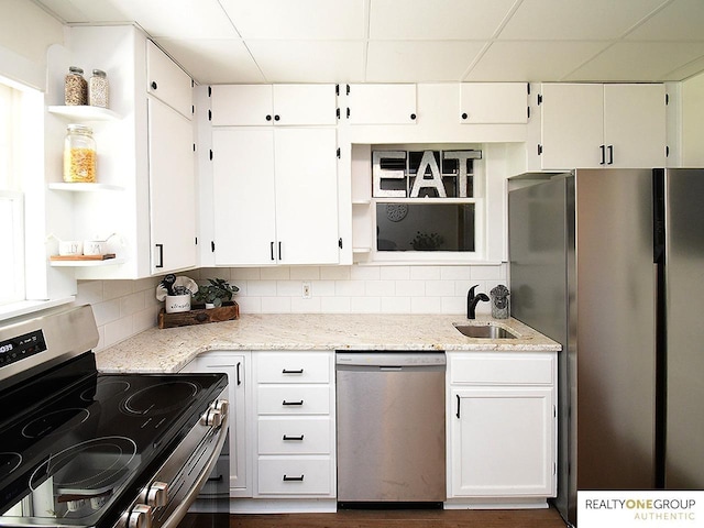 kitchen with appliances with stainless steel finishes, open shelves, a sink, backsplash, and a paneled ceiling