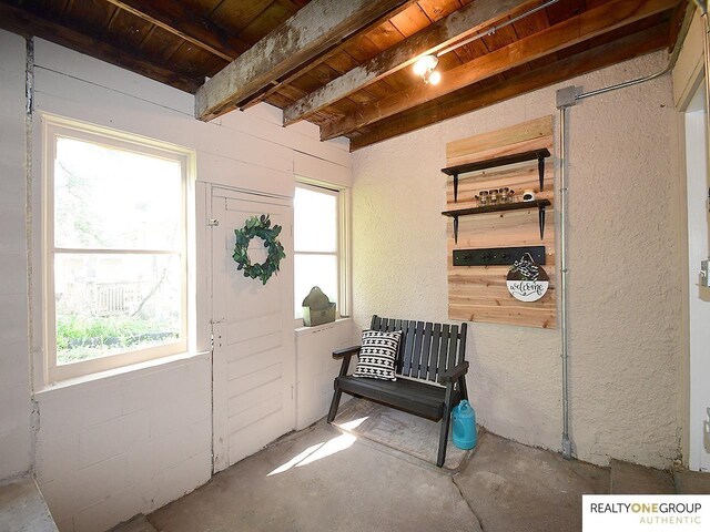 sitting room with wooden ceiling, unfinished concrete floors, and beamed ceiling