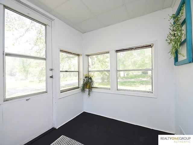 doorway with plenty of natural light, a drop ceiling, and baseboards