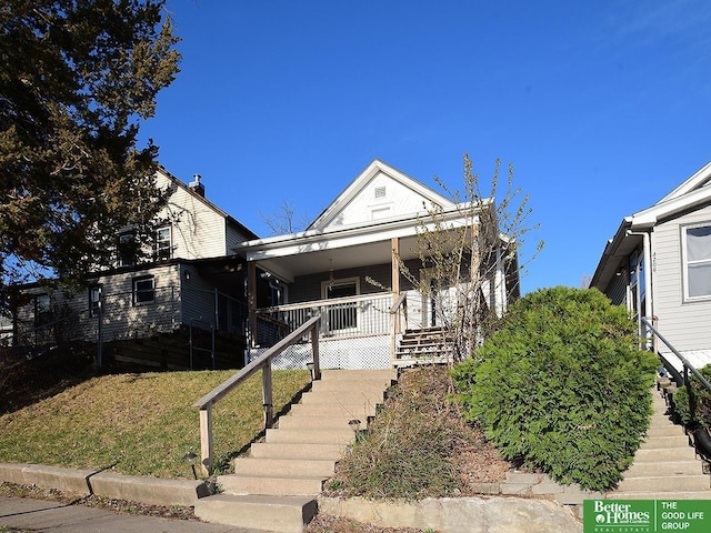 4210 S 21st St, Omaha, NE 68107 - shotgun-style home with stairs, covered porch, and a front lawn