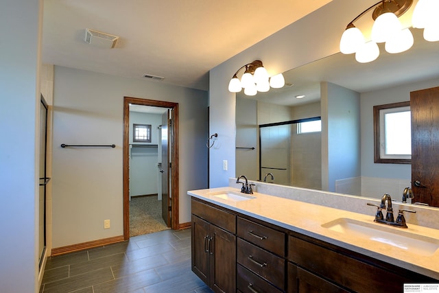 bathroom featuring a shower with door, baseboards, double vanity, and wood finish floors