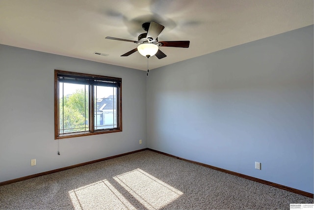 carpeted spare room featuring a ceiling fan and baseboards