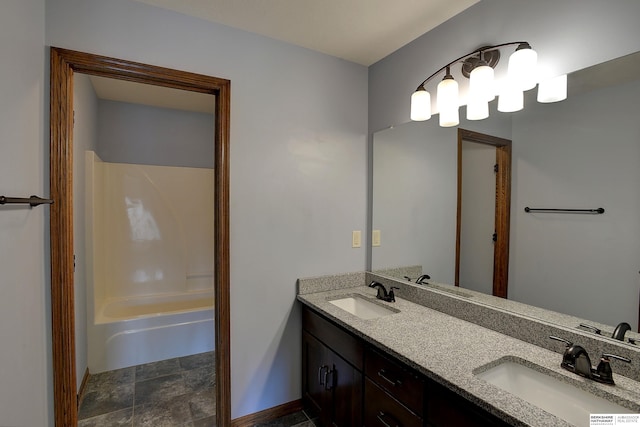 full bathroom featuring double vanity, stone finish flooring, and bathtub / shower combination