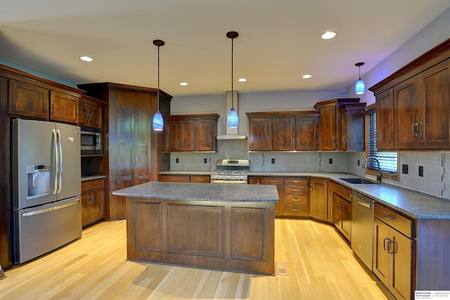 kitchen with stainless steel appliances, wall chimney range hood, a sink, light wood-type flooring, and decorative backsplash
