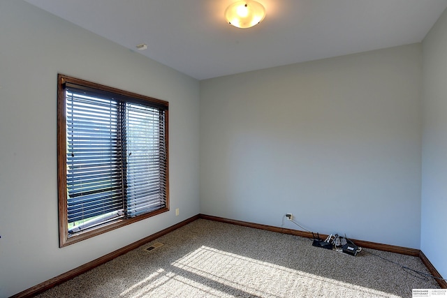 carpeted spare room featuring baseboards