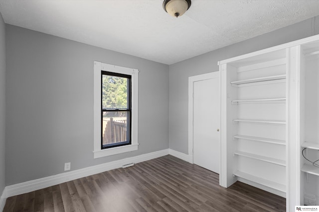 unfurnished bedroom with dark wood-style floors, a closet, baseboards, and a textured ceiling