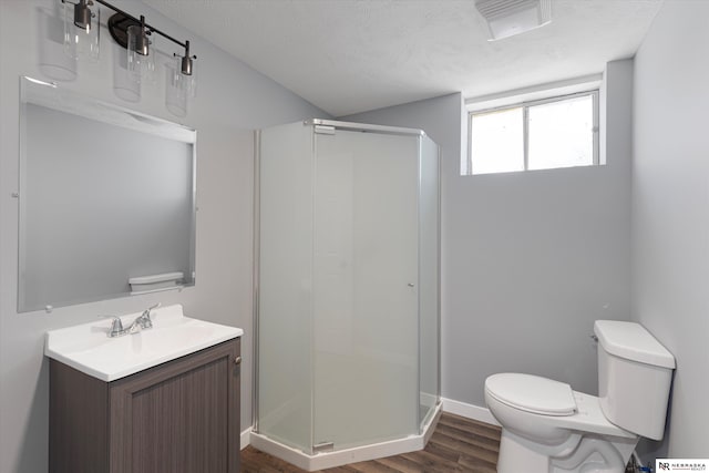 bathroom with toilet, a stall shower, wood finished floors, and a textured ceiling