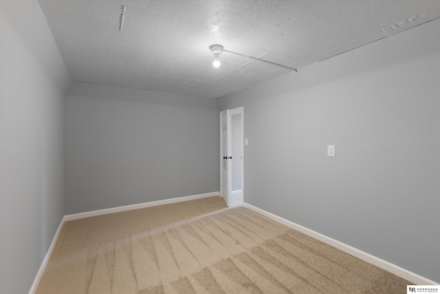 unfurnished room with carpet floors, a textured ceiling, and baseboards