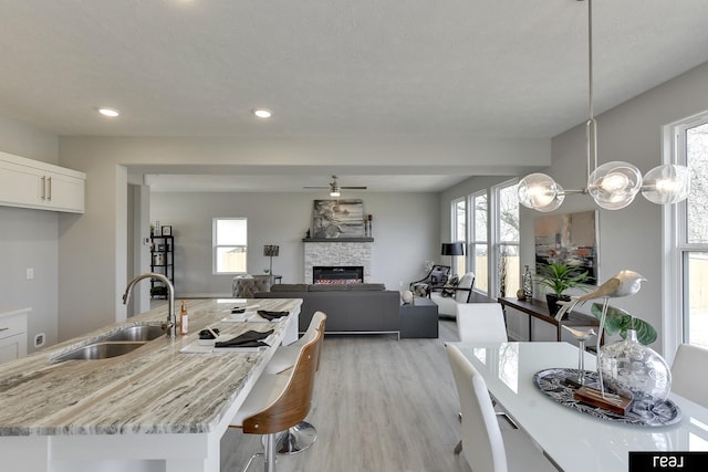 4406 Barksdale Dr, Bellevue, NE 68123 - kitchen with a sink, white cabinetry, light wood-type flooring, a fireplace, and light stone countertops