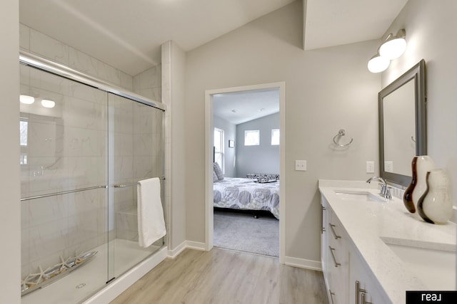 4406 Barksdale Dr, Bellevue, NE 68123 - bathroom featuring wood finished floors, vaulted ceiling, a stall shower, ensuite bathroom, and double vanity
