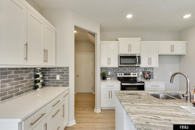 4406 Barksdale Dr, Bellevue, NE 68123 - kitchen with appliances with stainless steel finishes, a sink, light wood-style floors, white cabinetry, and recessed lighting