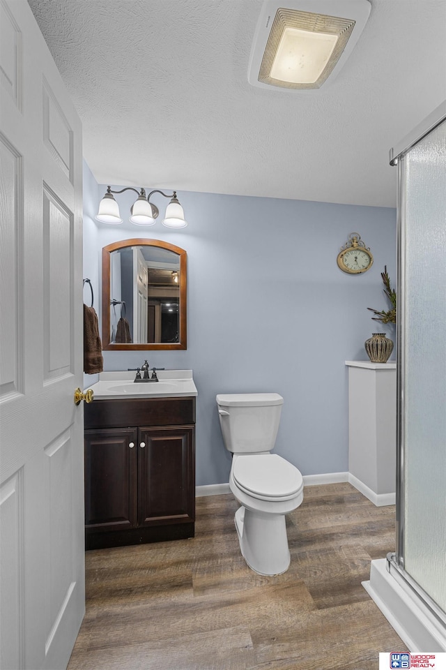 4511 E Eden St, Lincoln, NE 68506 - full bath featuring vanity, wood finished floors, toilet, an enclosed shower, and a textured ceiling