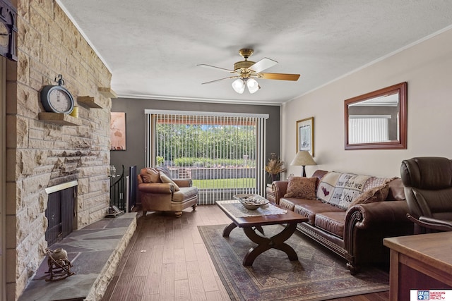4511 E Eden St, Lincoln, NE 68506 - living room with crown molding, ceiling fan, hardwood / wood-style flooring, a stone fireplace, and a textured ceiling