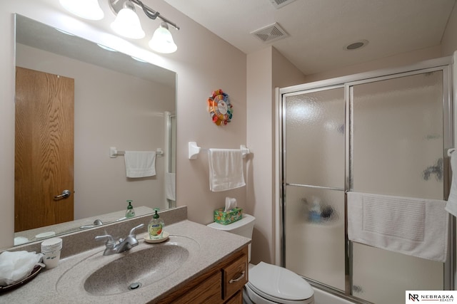 full bathroom featuring a shower stall, vanity, and toilet