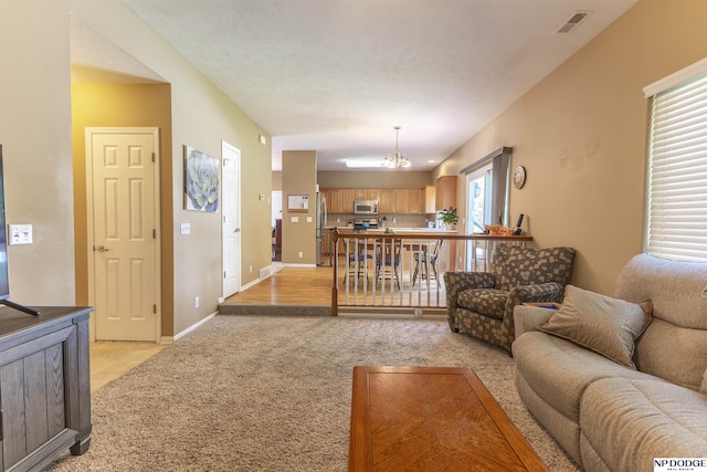 living room featuring light colored carpet, a chandelier, and baseboards