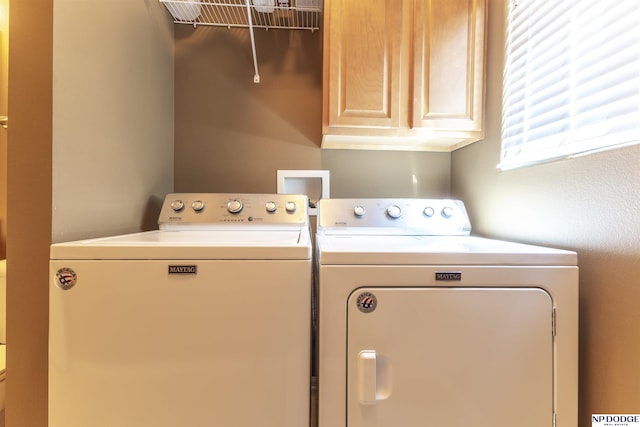clothes washing area with washer and clothes dryer and cabinet space