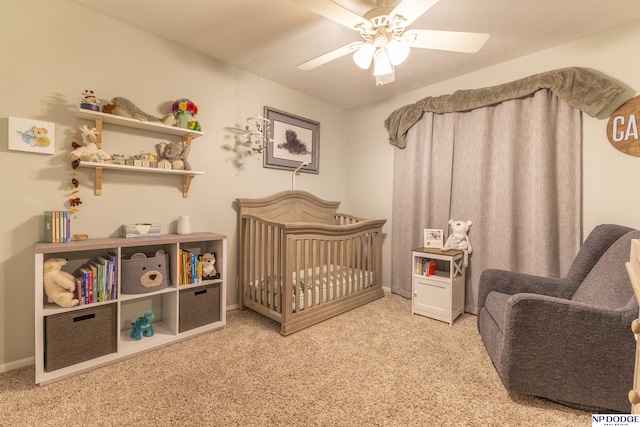 bedroom with a nursery area, carpet, ceiling fan, and baseboards