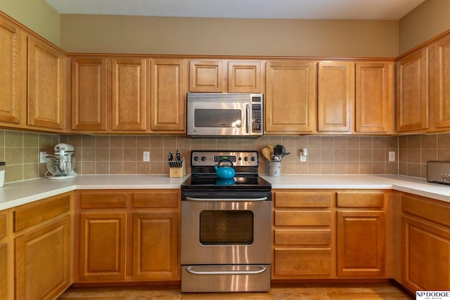 kitchen with appliances with stainless steel finishes, light countertops, and decorative backsplash