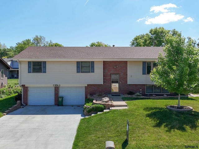 raised ranch featuring brick siding, driveway, an attached garage, a front lawn, and a shingled roof