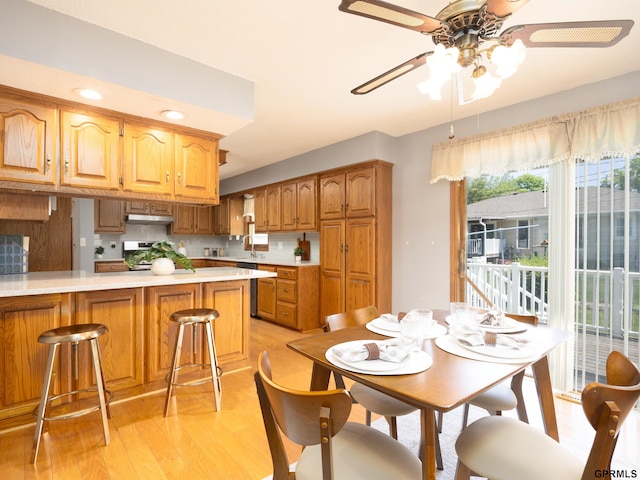 kitchen featuring light wood finished floors, a sink, under cabinet range hood, light countertops, and a ceiling fan
